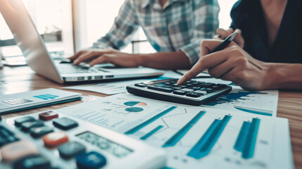 In economic business discussions, a team analyzes income charts and graphs, using a computer laptop and calculator to plan marketing strategies.
