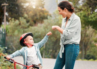 Parent, son and fist bump with hand for support, woman and kid with bicycle or gesture for motivation. Happiness, love and milestone for child development, home driveway and outside for trust or fun
