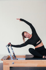 Young beautiful woman doing Pilates exercise on pilates reformer bed