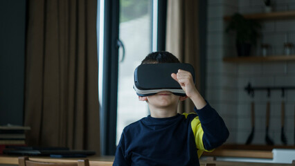 Obraz premium Young boy immersed in a virtual reality experience with a VR headset. The excitement and wonder of modern childhood, tech-savvy kid exploring digital worlds in home 