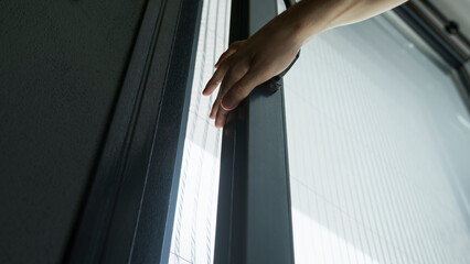 A close-up shot of a hand gripping and opening a sliding glass door.	
