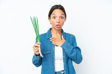 Young hispanic woman holding chive isolated on white background surprised and shocked while looking right