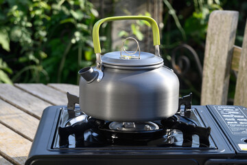 Kettle for camping on a gas stove. Making tea outdoors in the garden. Tourist kettle and stove.