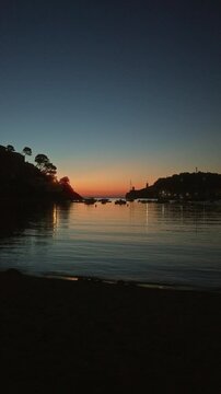 Sunset at port de soller with boats reflected on calm waters, mallorca, spain, showcasing a serene coastal landscape