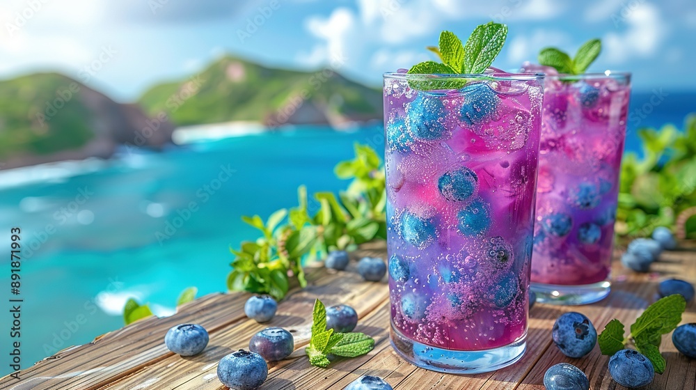 Wall mural   Two blueberry-filled glasses sit on a table beside a serene body of water, accented by a refreshing mint sprig