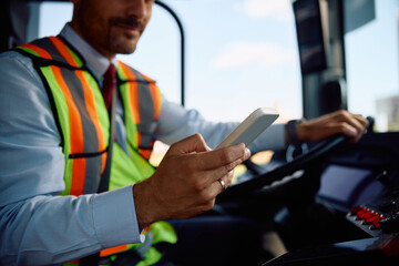 Close up of bus driver using cell phone while driving. © Drazen