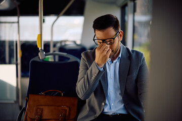 Exhausted businessman having  headache while commuting by bus.