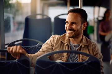Happy man enjoying in city bus ride while looking through window. © Drazen