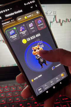 Moscow, Russia-June 20, 2024:A man clicks his finger on the smartphone screen in the game Hamster Combat. Hamster Kombat tap 2 earn mini game in telegram messenger on smartphone display close up