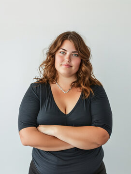 Jeune femme ronde souriante, personne de forte taille debout bras crois&eacute; sur fond blanc, diversit&eacute; des corps, body positive, T-shirt noir sur arri&egrave;re-plan blanc