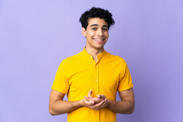 Young Venezuelan man isolated on purple background laughing