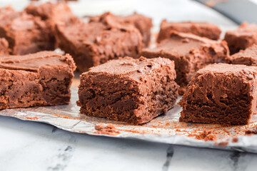 Brownie squares with chocolate frosting arranged on foil