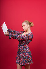 A woman in a purple floral dress is holding a tablet computer