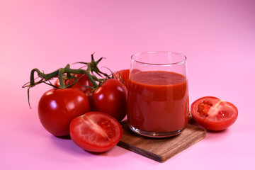 tomato juice with fresh tomatoes on a pink background. A fragrant drink.