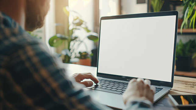 Over shoulder shot of a young man using computer laptop in front of an blank white computer screen in home