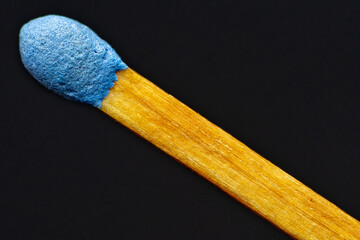 Match stick with blue head in day on black background.