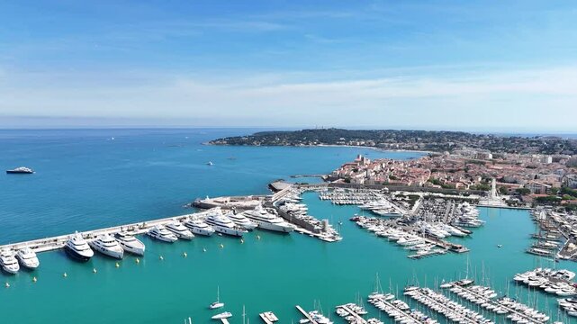 Drone shot of Antibes, France, featuring the beach, church, marina with boats, and the stunning C&ocirc;te d'Azur coastline along the Mediterranean Sea.