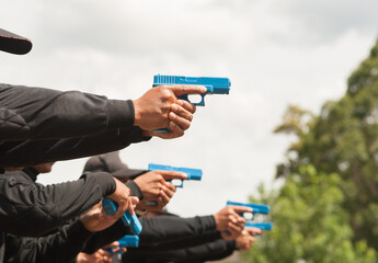 Police practice using blue rubber firearms in the lawn. - obrazy, fototapety, plakaty