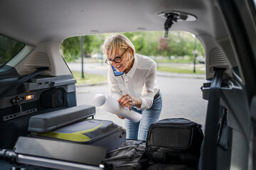 mature blonde woman travel take stuff belongings from the back of car