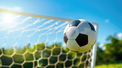 Naklejka premium Soccer ball flying towards goal net in bright sunlight