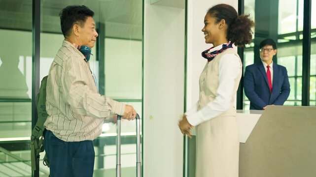 Air hostess stand in front of security gate to service Asian and Caucasian customer before register at service counter at the airport.