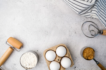 Baking pastry and cake ingredients with wooden utensil on light stone concrete, top view, flatlay with copy space.