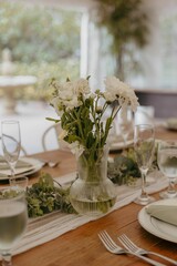 Elegant table setting with floral centerpiece in a glass vase, ready for a special occasion.