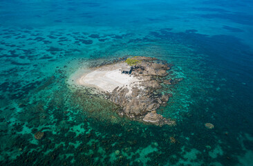Aerial view of a small tropical island on an atoll with beautiful sandy beach surrounded by coral reef. Tropical island and coral reef. Summer and travel vacation concept