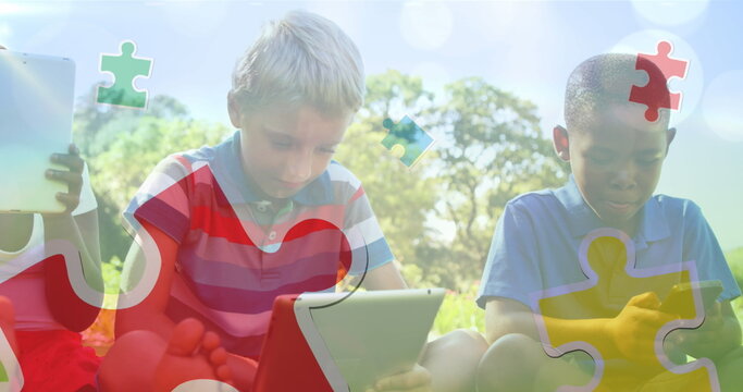 Image of colourful puzzle pieces over school children using tablets