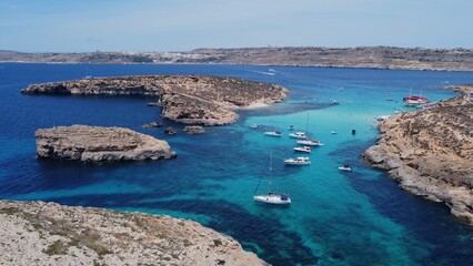 Boats floating in the crystal clear turquoise sea water. Blue lagoon, Comino, Maltese Islands. Aerial establishing view. High quality photo