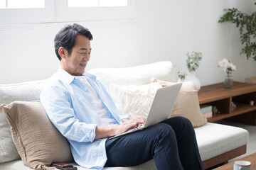 綺麗なリビングでノートパソコンを使う50代の男性