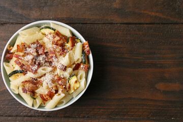 Tasty pasta with bacon and cheese on wooden table, top view. Space for text