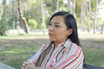Woman seated in a public park with an attitude of preoccupation, pensive.