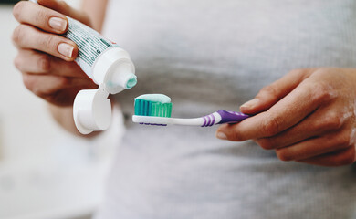 Woman, hands and toothbrush with toothpaste for dental care, hygiene or morning routine at home. Closeup of female person applying paste on bristle for tooth whitening, oral or cleaning at house