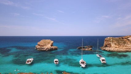 Comino, Malta 29.05.2024 - Boats anchored near Blue lagoon, Cominotto island in the back. Revealing shot. High quality photo