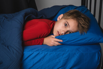 Young frightened preteen boy in bed wearing red pajamas © 303Photos.com