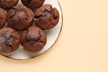 Plate with tasty chocolate cupcakes on beige background, closeup