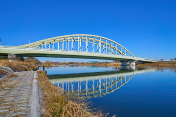 Obraz premium 川崎市多摩区の稲田多摩川公園付近から多摩川に水面反射する多摩水道橋を見る