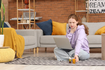 Sick young woman with sore throat, laptop and medicine at home
