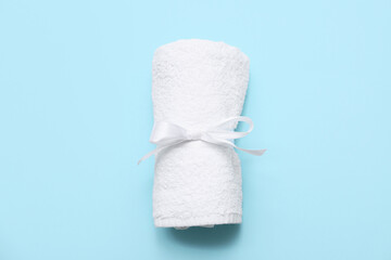 Rolled clean soft towel with silk ribbon on blue background