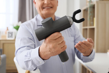 Mature businessman with percussive massager in office, closeup
