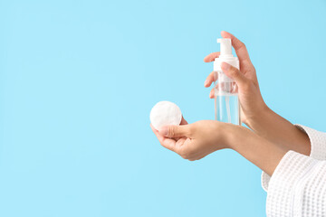 Young woman with makeup remover and cotton pad on blue background, closeup © Pixel-Shot