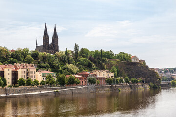 Fototapeta premium View from the embankment of Vltava river to Railway Bridge and Saints Peter and Paul Basilica in Vysehrad in Prague in Czech Republic