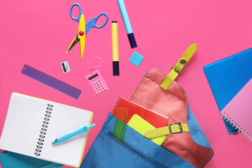 Backpack with different school stationery flying on pink background