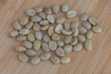 The process of coffee beans being dehulled and yellowing, scattered on the wooden table, showing their natural state