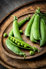 Green young sweet peas arranged beautifully on wooden plates, rustic, close-up.