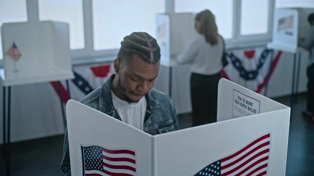 African American man comes to vote in booth in polling station office. National Election Day in the United States. Political races of US presidential candidates. Concept of patriotism and civic duty.