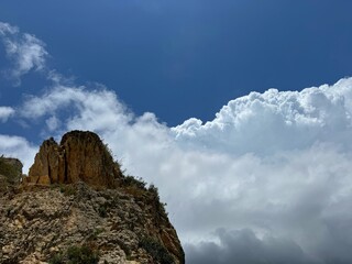 Top of the rock against white clouds in the sky 