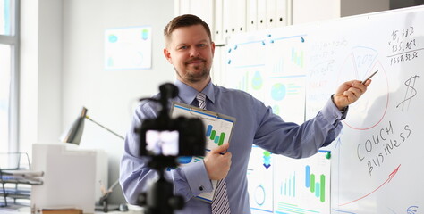Male in suit and tie show stats graph pad making promo videoblog or photo in office camcorder to tripod portrait. Vlogger selfie solution or finance advisor management information professional concept © H_Ko