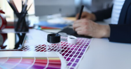 Test print paper page with colour test design fantail and magnifying glass lying at worktable for further promotion closeup